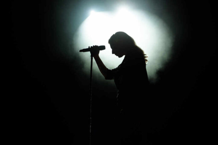 Black,Silhouette,Of,Female,Singer,With,White,Spotlights,In,The