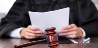 A judge holding documents with a gavel in the foreground