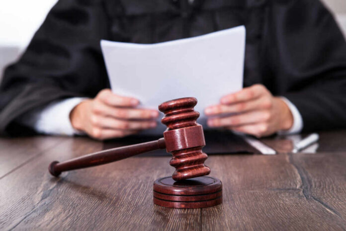 A judge holding documents with a gavel in the foreground
