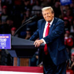 A speaker at a political rally smiling while addressing the audience