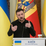 Ukrainian leader delivering a speech at a podium with national flags in the background