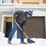 Senior man shoveling snow in front of a house