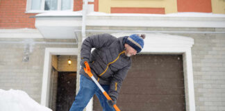 Senior man shoveling snow in front of a house