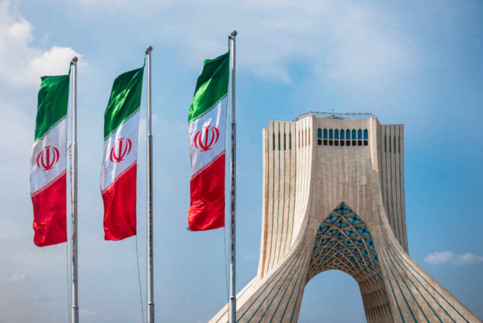 shutterstock_505715608.jpg Three Iranian flags in front of the Azadi Tower against a blue sky
