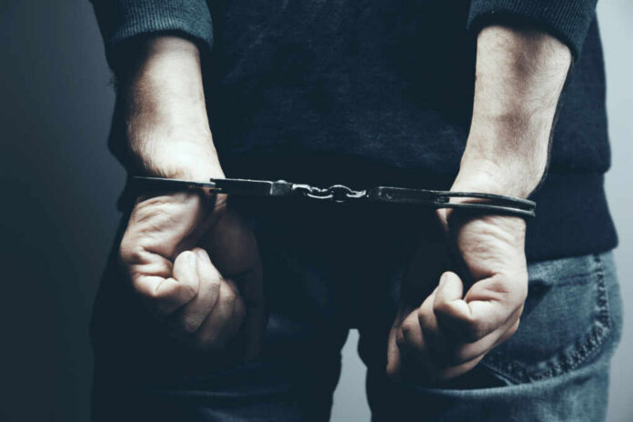 A person in handcuffs with their hands behind their back