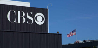 CBS logo on a building with an American flag in the background