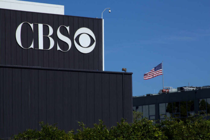 CBS logo on a building with an American flag in the background