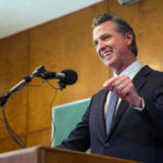 A man in a suit delivering a speech at a podium with microphones