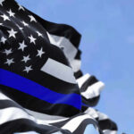 Thin blue line flag waving against a blue sky