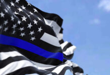 Thin blue line flag waving against a blue sky