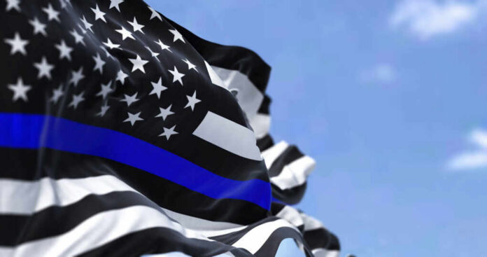 Thin blue line flag waving against a blue sky