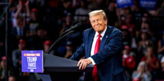 A speaker at a political rally smiling while addressing the audience