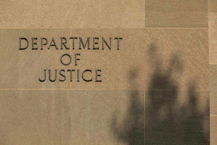 Sign reading Department of Justice on a stone wall with a shadow