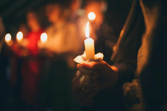 People holding lit candles in a dimly lit setting