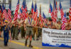 Boy Scouts marching in a parade carrying American flags