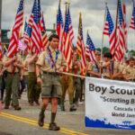 Boy Scouts marching in a parade carrying American flags