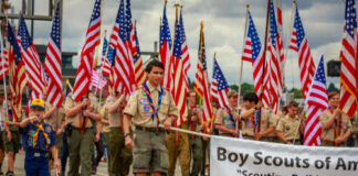 Boy Scouts marching in a parade carrying American flags