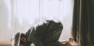 A child in traditional attire kneeling in prayer indoors