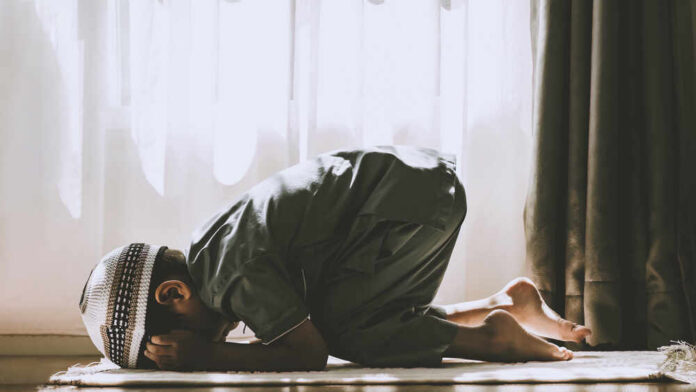 A child in traditional attire kneeling in prayer indoors