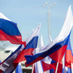 Multiple Russian flags waving in the wind at an outdoor event