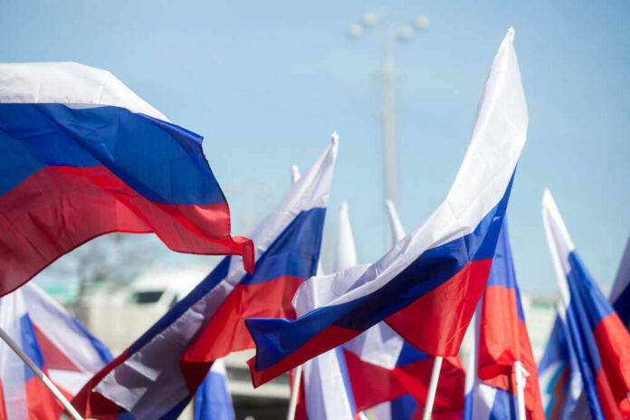 Multiple Russian flags waving in the wind at an outdoor event