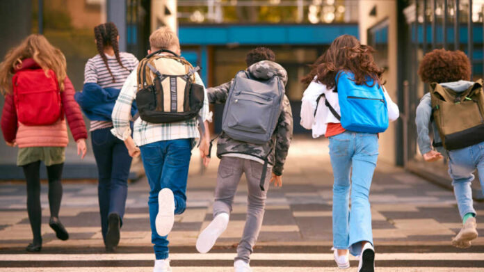 shutterstock_2394500109.jpg Group of children walking together with backpacks in an urban area