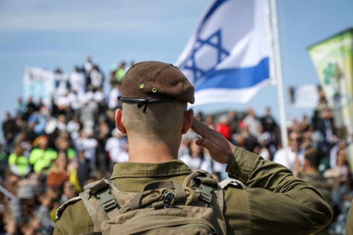 Soldier saluting in front of a crowd with the Israeli flag in the background