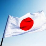 Japanese flag with a red circle on a white background waving against a blue sky