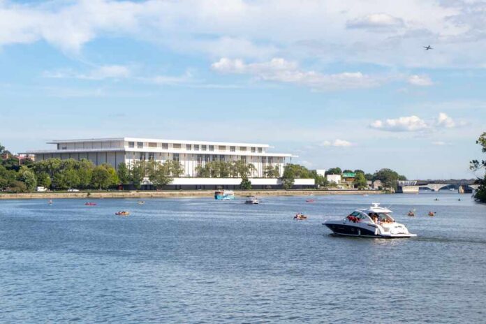 A scenic view of a river with boats and a modern building in the background