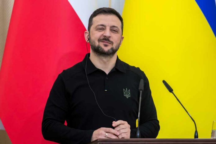A political leader speaking at a press conference with flags in the background