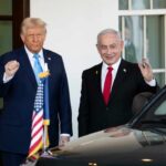 Two political leaders standing outside the White House, one raising a fist and the other waving