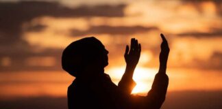 Silhouette of a person with raised hands against a sunset