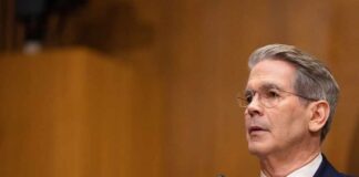 A man in formal attire speaking at a government hearing