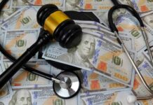 A gavel and stethoscope placed on a background of hundred-dollar bills