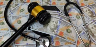 A gavel and stethoscope placed on a background of hundred-dollar bills