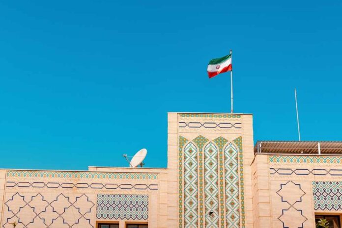 Building with intricate patterns and the Iranian flag against a clear blue sky