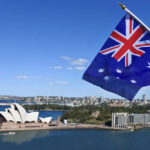 Australian flag waving in front of the Sydney Opera House and city skyline