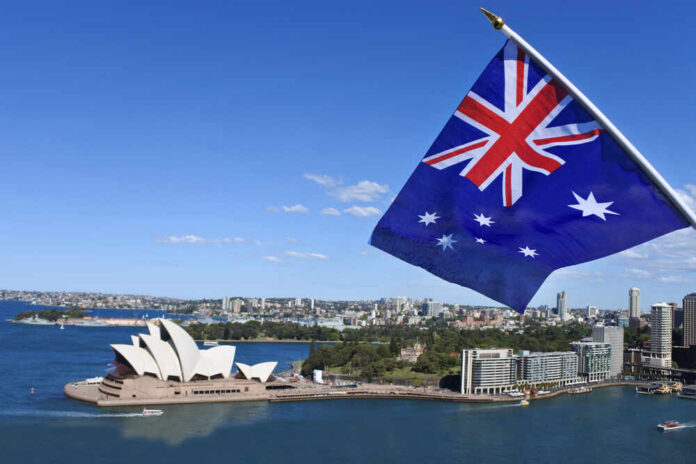 Australian flag waving in front of the Sydney Opera House and city skyline