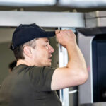 Man wearing a cap interacting with a technological device indoors