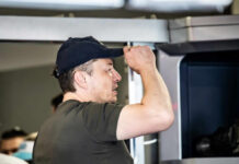 Man wearing a cap interacting with a technological device indoors