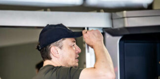 Man wearing a cap interacting with a technological device indoors