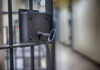 Close-up of a locked jail cell door with a key inserted