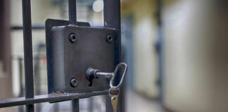 Close-up of a locked jail cell door with a key inserted