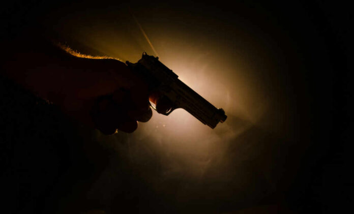 shutterstock657785272jpg Silhouette of a hand holding a handgun against a dramatic light background