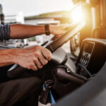 Close-up of a truck driver's hands on the steering wheel inside a vehicle