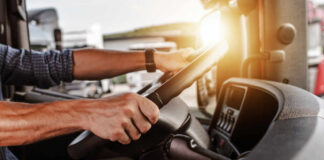Close-up of a truck driver's hands on the steering wheel inside a vehicle