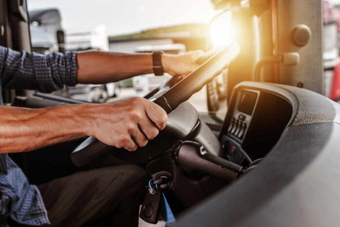 Close-up of a truck driver's hands on the steering wheel inside a vehicle