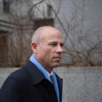 Man in business attire walking outdoors with a serious expression