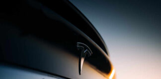Tesla-Uber Integration Sparks Controversy Close-up of a Tesla logo on a black car with a sunset in the background