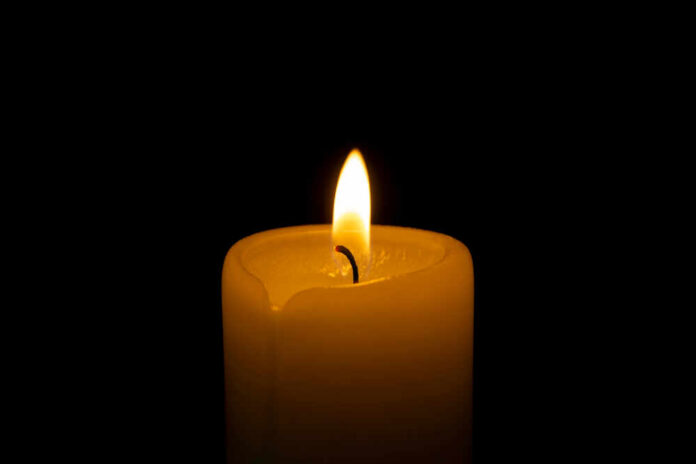 A lit candle with a soft flame against a black background